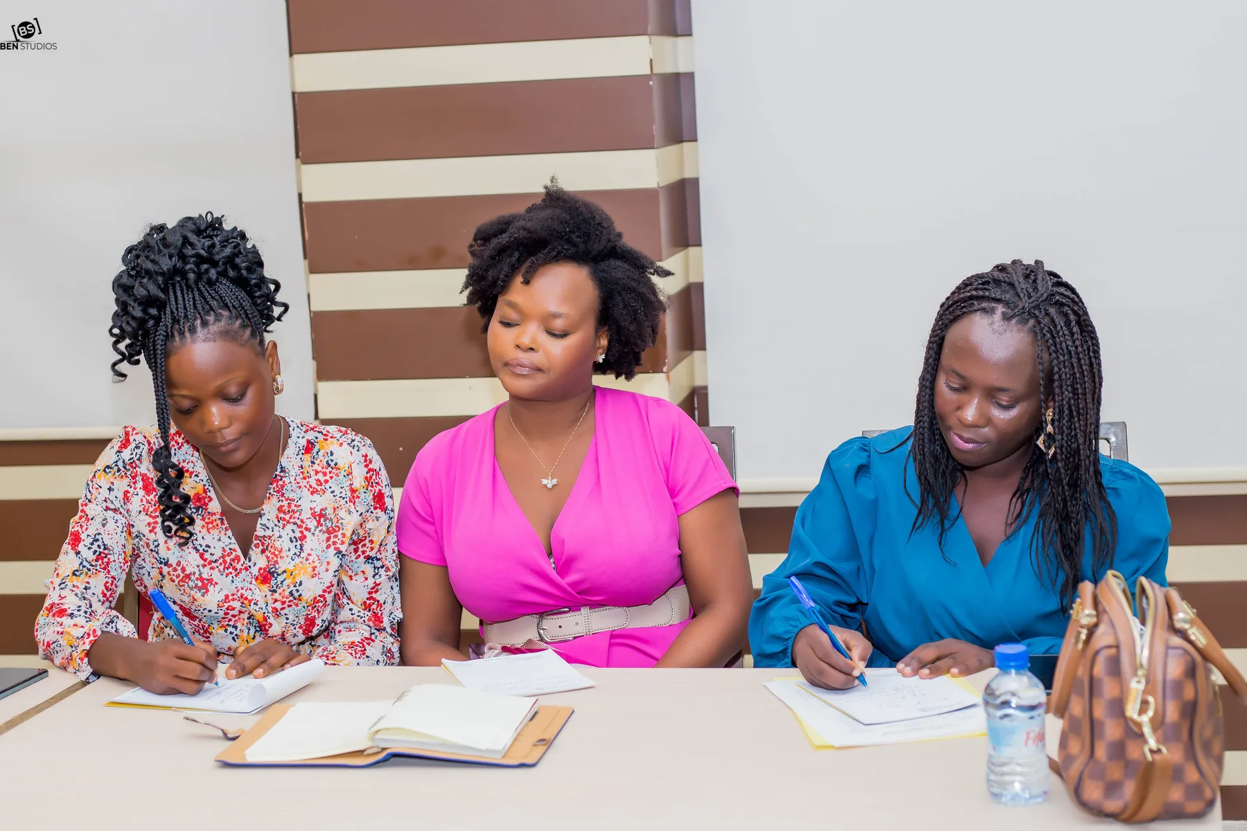 Trois participantes de Conversations Inspirantes, concentrées, prennent des notes
