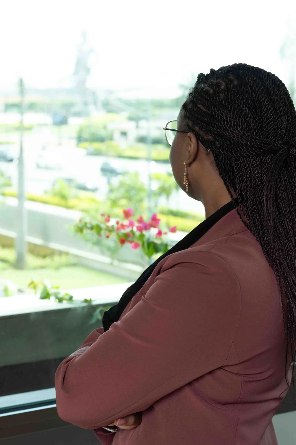 La Présidente d’Honneur, de dos, regarde par la fenêtre vers la statue de l’Amazone à Cotonou