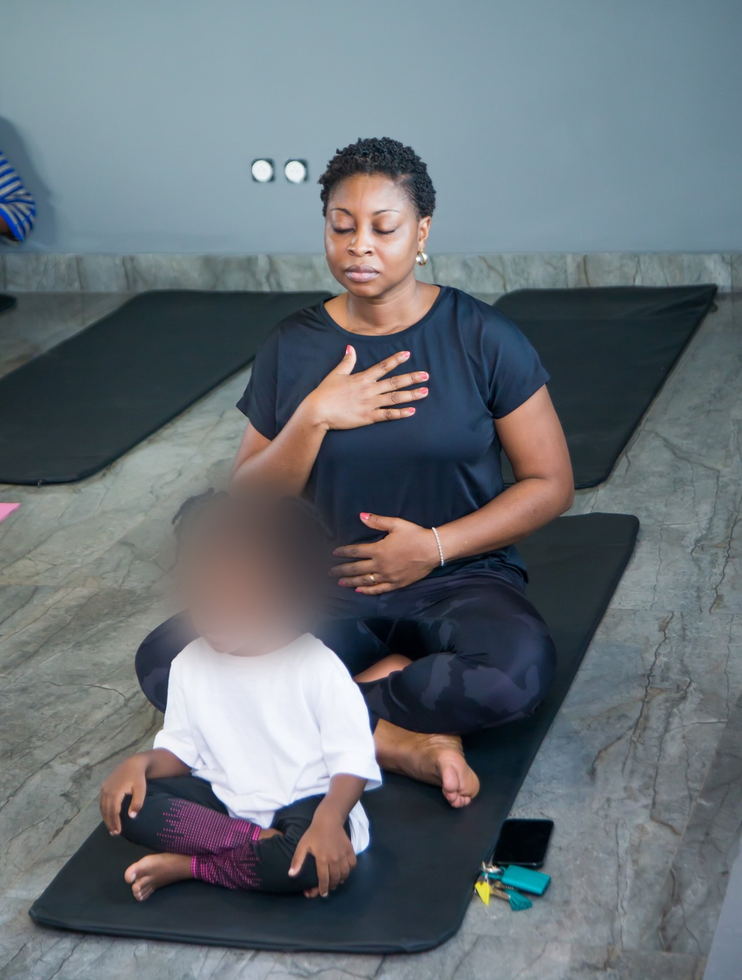 Aurélie Adam Soulé assise en posture de yoga, avec le visage de l’enfant flouté